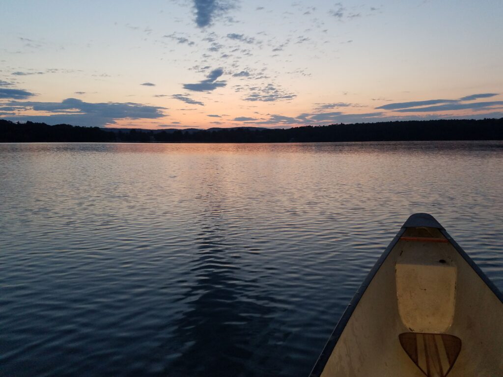 sunrise on Lake Wononscopomuc with a portion of both my canoe and my paddle visible in the foreground
